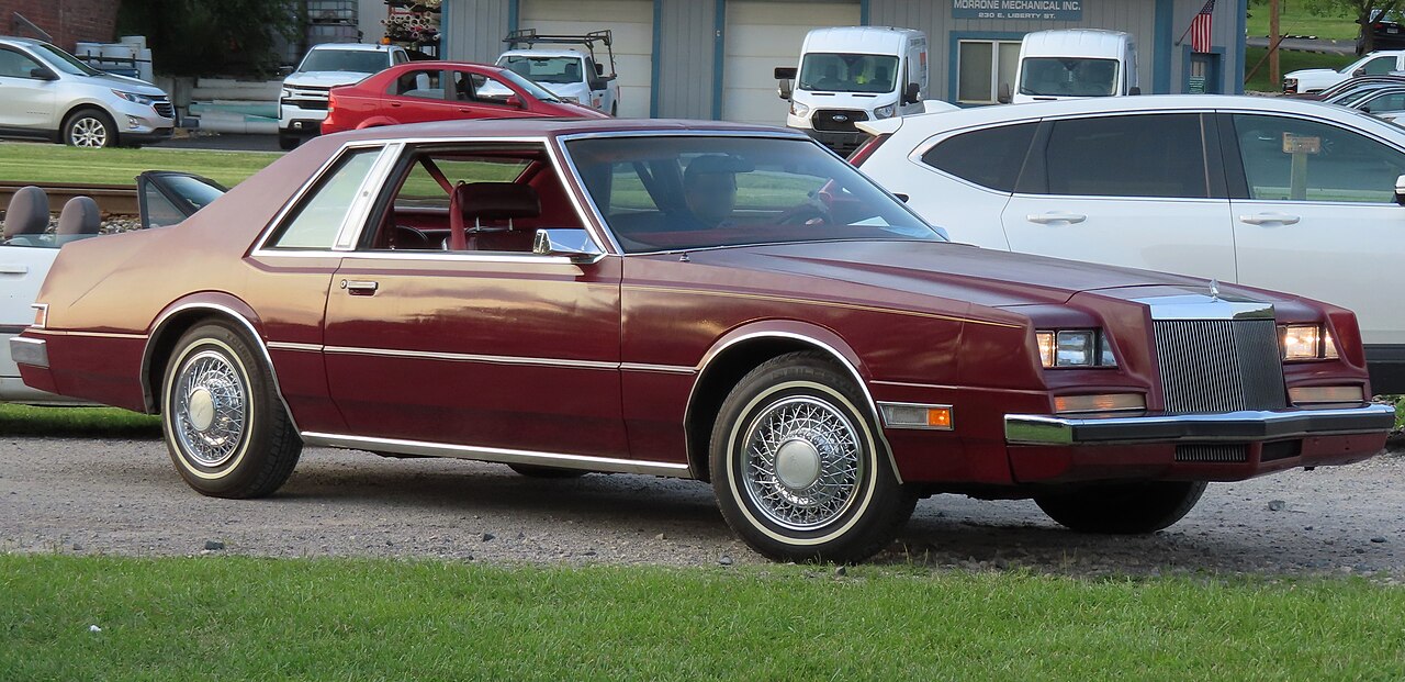 Chrysler Imperial 1981 w kolorze Morocco Red, coupe J-body sfotografowane od prawego przodu z otwartymi osłonami reflektorów