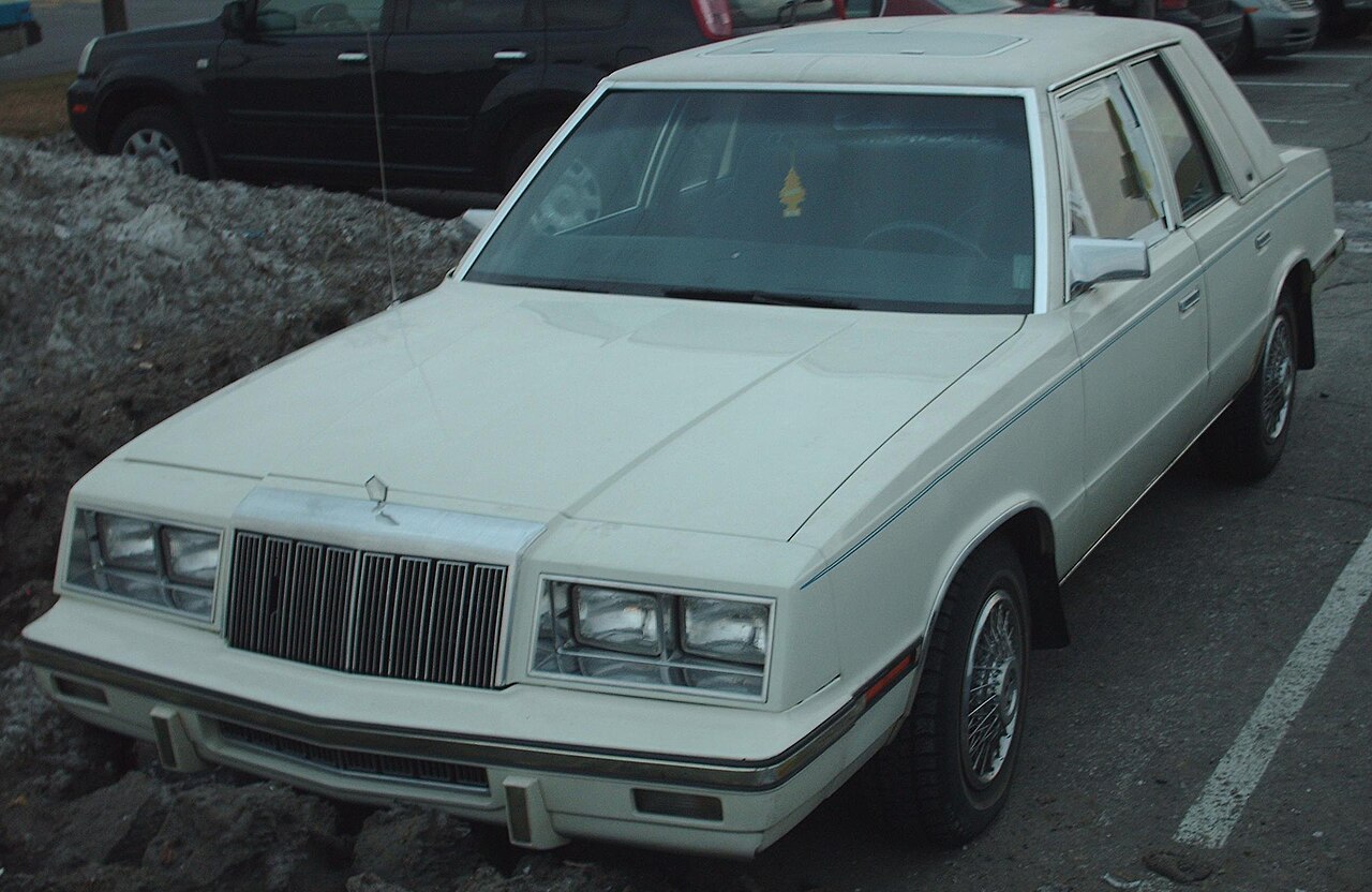 Biały Chrysler LeBaron sedan pierwszych lat rodziny K-body 1982-1984, nadwozie czterodrzwiowe z napędem na przednie koła